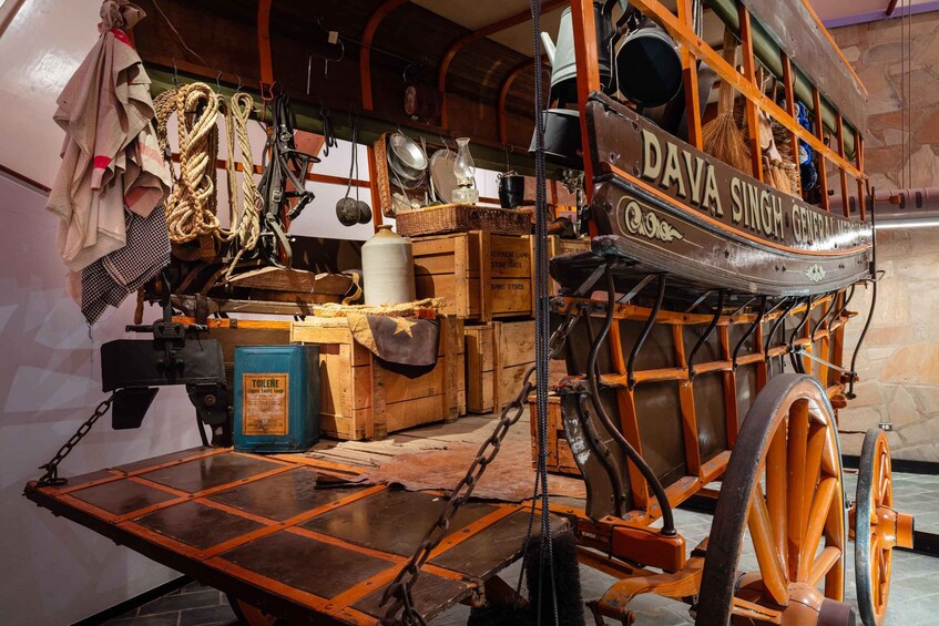 Ein alter Karren mit dem Schild 'Dava Singh General Store', beladen mit verschiedenen Artikeln wie Seilen, Körben und einer Petroleumlampe. 4