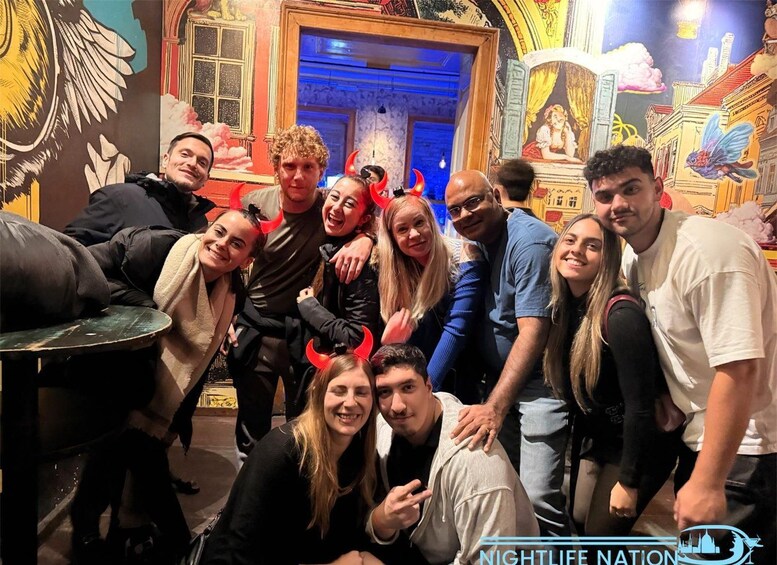 A group of people posing in a room with artistic murals and a blue-lit doorway. 5