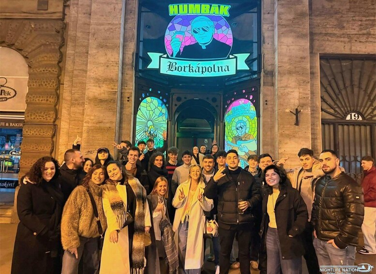 A group of people in front of a building with a sign that reads 'HUMBÁK Borkápolna.' 3