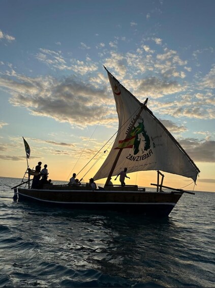 A traditional sailing boat with a dragon design on its sail, sailing on calm waters during sunset. 2