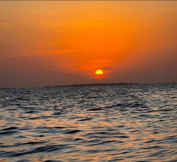 A sunset over a calm sea with a distant shoreline. 1