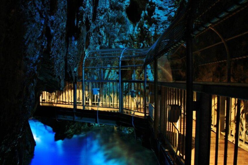 A cave with a glass walkway, a small stream, and a metal railing. 4