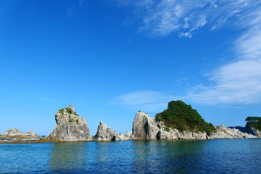 A calm sea with rocky outcrops and clear blue sky. 2
