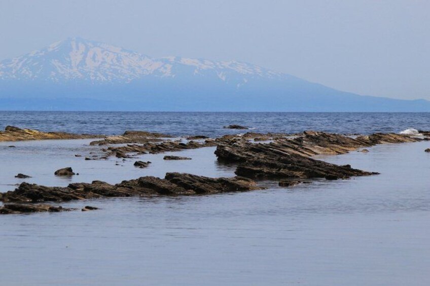 A rocky shoreline with a mountain range in the background. 5