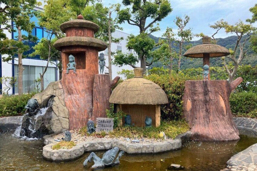 A garden with a pond, a thatched-roof hut, and stone structures. 5