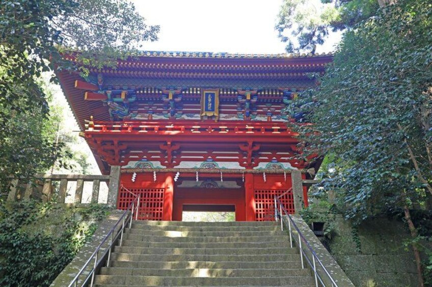 A traditional Chinese gate with red pillars and intricate designs, surrounded by lush greenery. 5