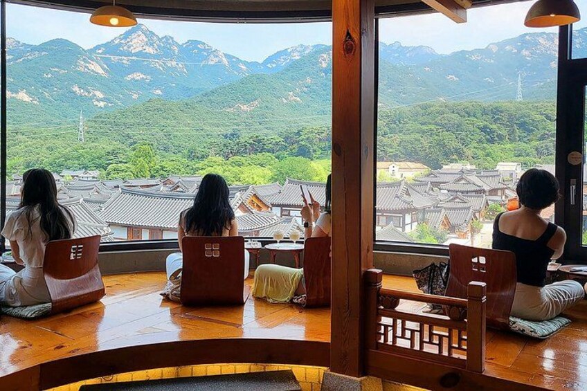 A group of people sitting on tatami mats in a traditional Japanese room with a view of a mountainous landscape. 4