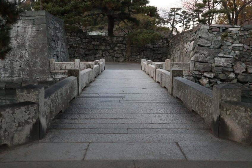 A stone pathway leading through a stone wall, surrounded by trees. 5