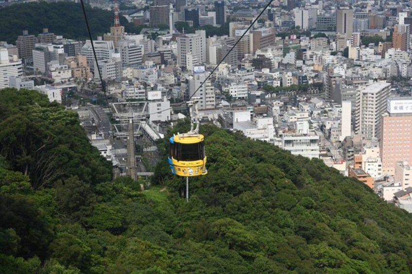 A cable car system in a cityscape with dense urban buildings and lush green hills. 4