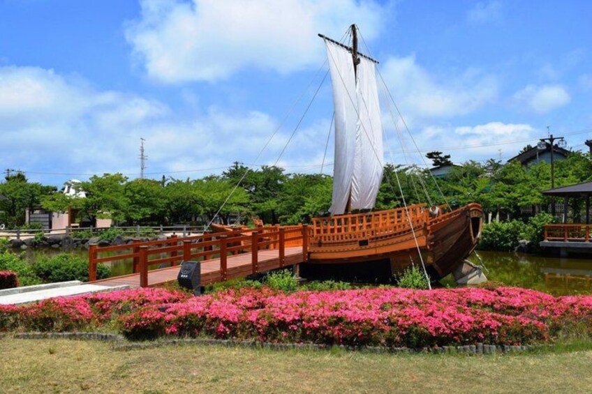 A traditional boat on a wooden dock, surrounded by pink flowers and greenery. 3