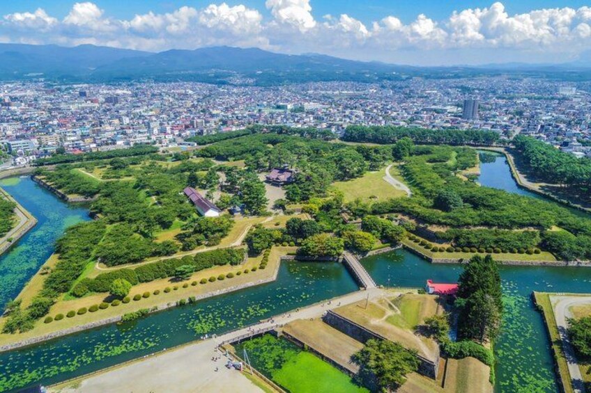 An aerial view of a city with a large park, a river, and a bridge. 5