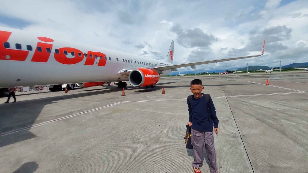 A person standing in front of a Lion Air airplane on the tarmac. 5