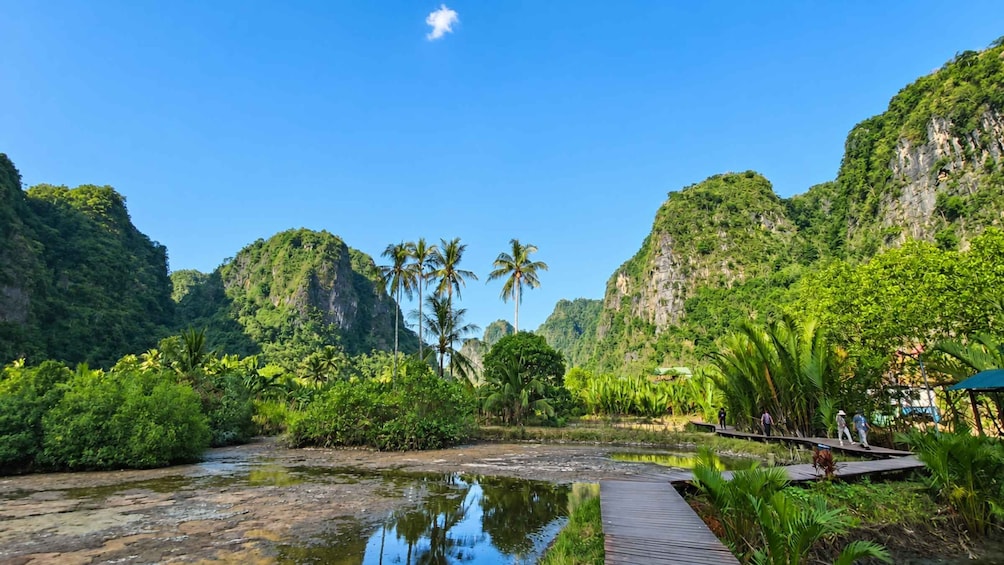 A river with a wooden walkway, surrounded by lush greenery and tall cliffs. 1