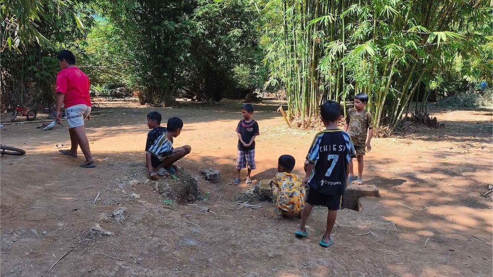 Children playing outdoors in a natural setting with trees and dirt ground. 5