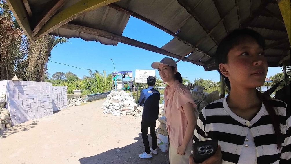 A rural setting with a dirt road, a covered structure, and a signboard. 4