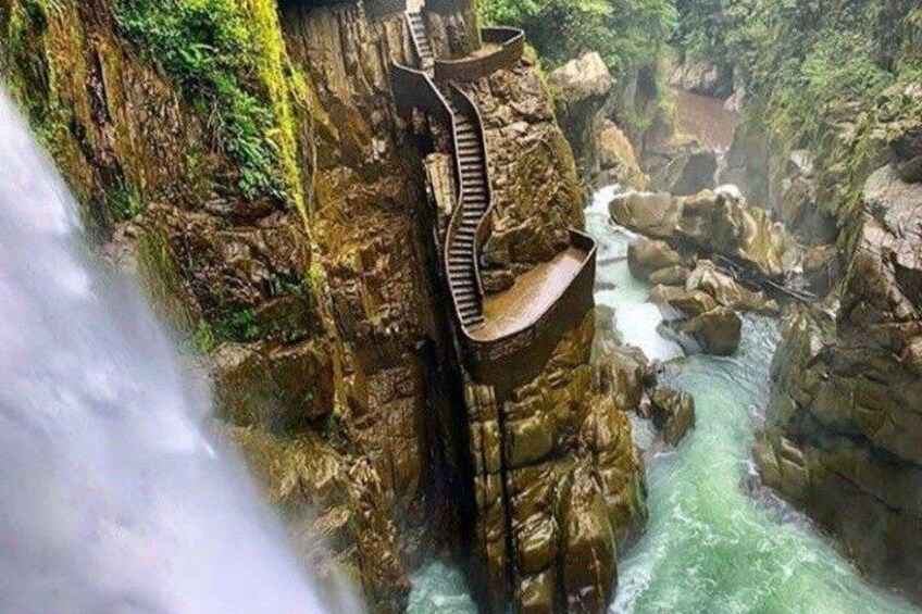A waterfall cascading down a rocky cliff with a wooden staircase leading down. 5