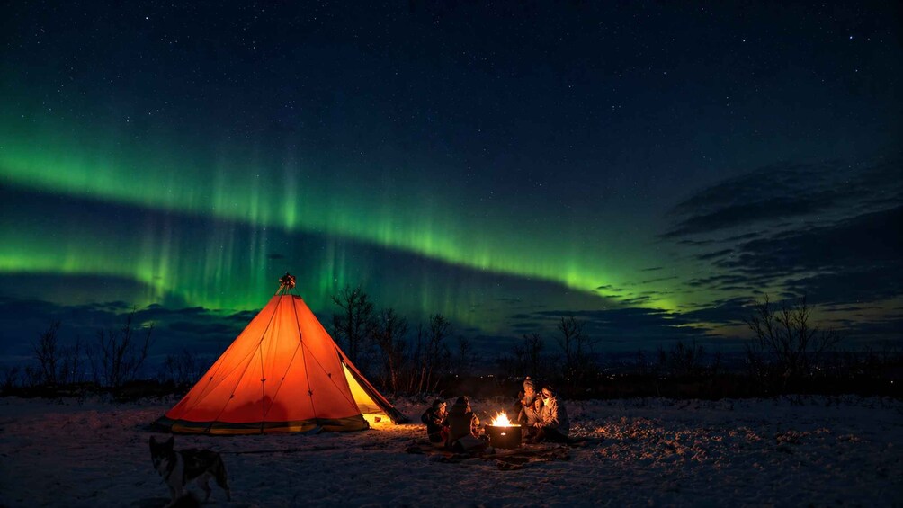 A tent under the Northern Lights with a campfire. 1