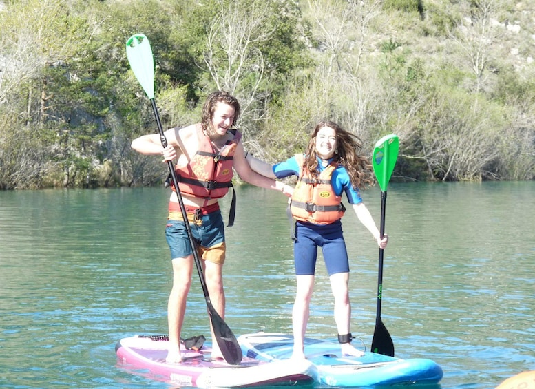 Two people on paddleboards in a body of water with trees in the background. 5