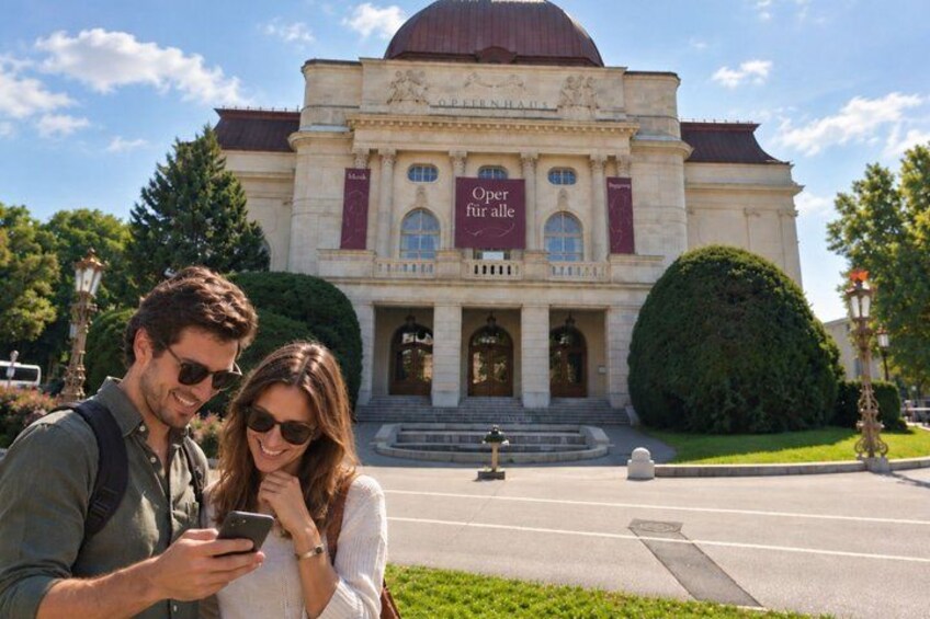 A couple standing in front of a building with a dome and a sign that reads 'Oper fur alle.' 4