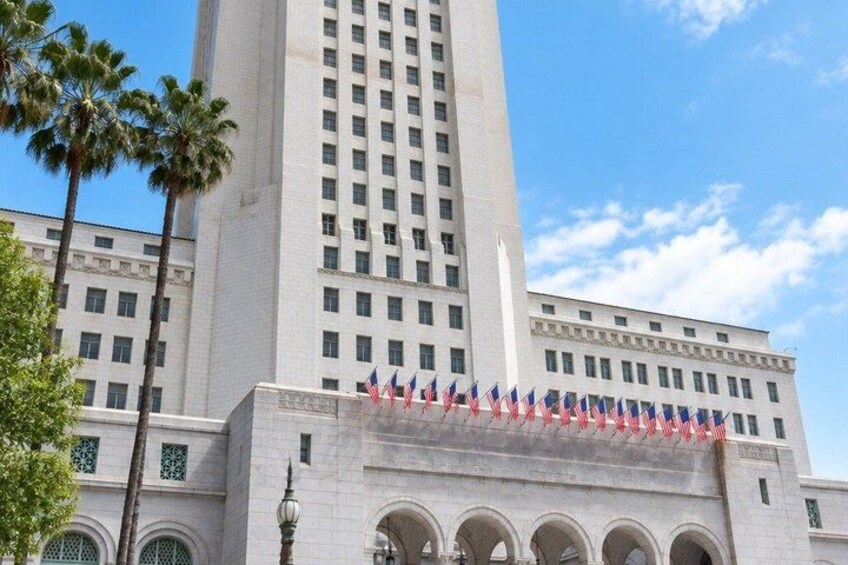 A tall white building with multiple windows and a flag display. 2