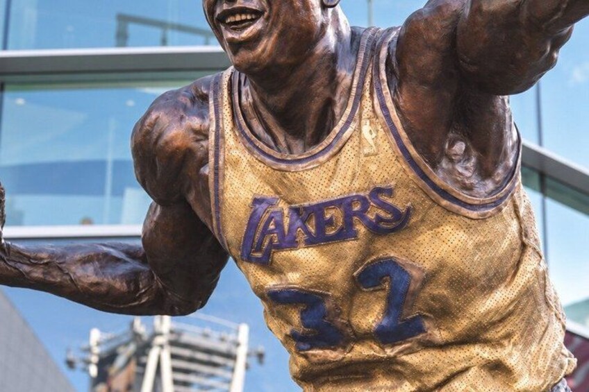 A bronze statue of a basketball player in a Lakers jersey with the number 32. 5
