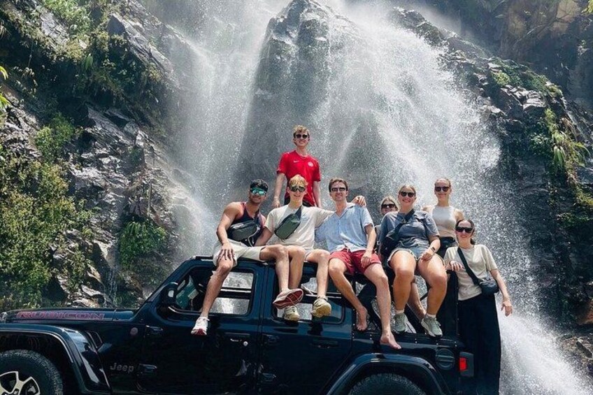 A group of people on a vehicle in front of a waterfall. 5
