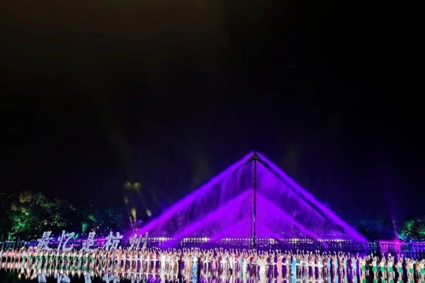 A large crowd gathered around a pyramid-shaped structure illuminated by purple lights. 4