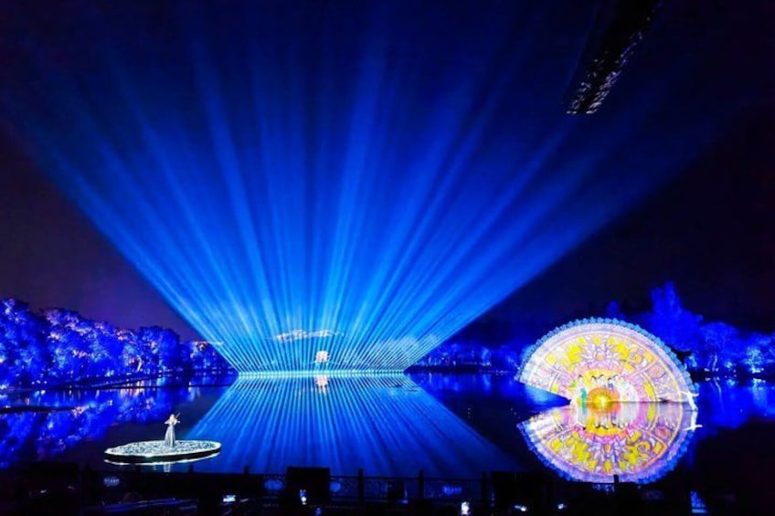 A night scene with a large Ferris wheel illuminated by colorful lights, a fountain, and a stage with blue laser lights. 5