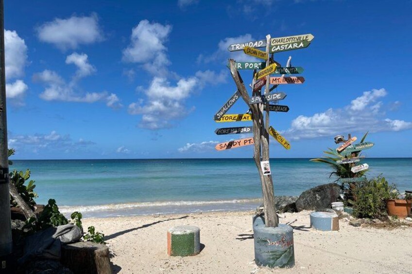 A beach with a signpost pointing to various destinations. 3