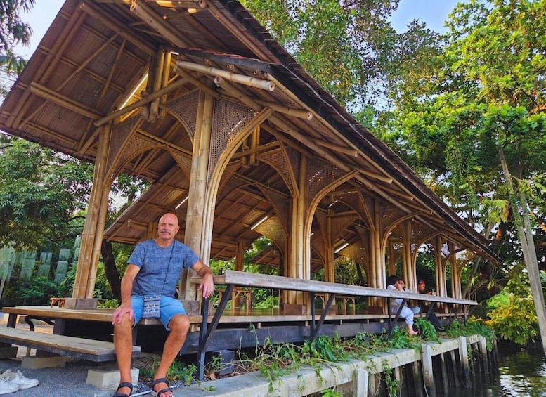 A wooden pavilion with a thatched roof, surrounded by lush greenery and a body of water. 5