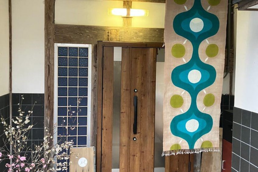 A wooden door with a glass panel, a decorative wall hanging, and a vase with flowers. 3