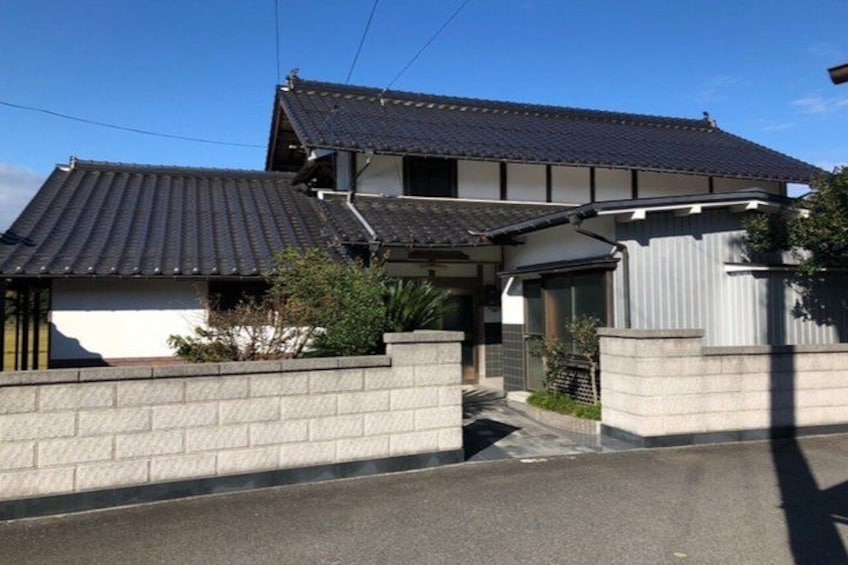 A two-story house with a dark tiled roof, a white exterior wall, and a concrete driveway. 2