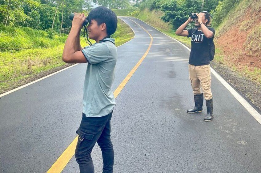 Two people taking photographs on a curved road with greenery on both sides. 5