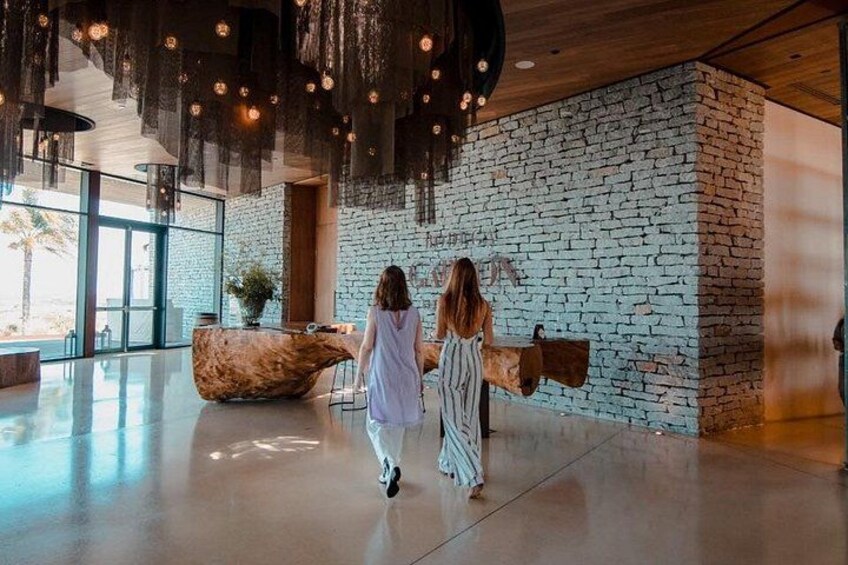 A spacious lobby with a stone wall, a wooden reception desk, and hanging lights. 2