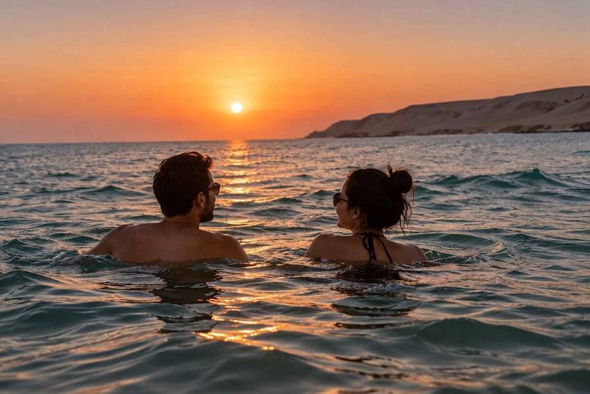 Two people swimming in the ocean at sunset with a sunset in the background. 5