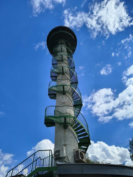 A spiral staircase structure with a clear blue sky and clouds in the background. 5