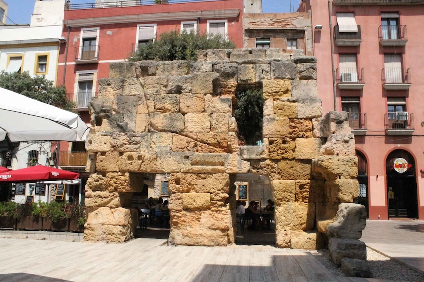 An ancient stone structure with a partially intact wall and a visible doorway. 4