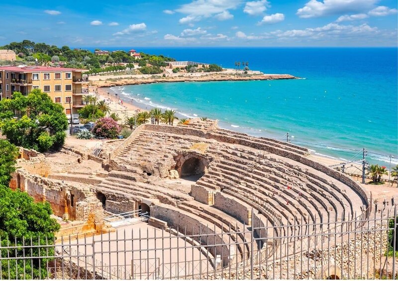 An ancient amphitheater with a beach and ocean in the background. 1