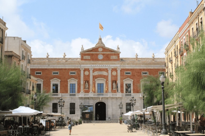 A historic building with a central entrance, columns, and a flag. 2