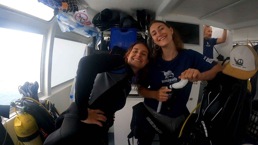 Two people in a vehicle with scuba gear and a blue bag. 3