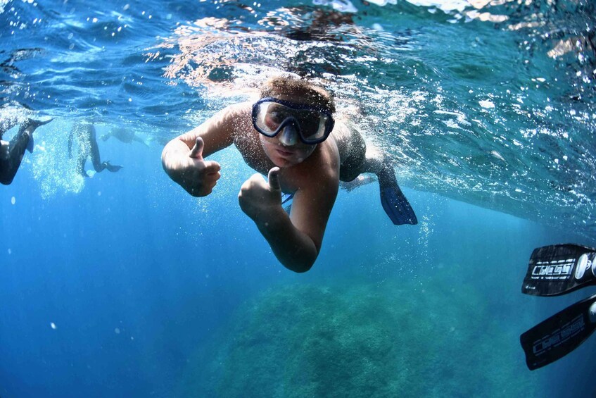 A person underwater giving a thumbs-up, with a snorkel and fins visible. 1