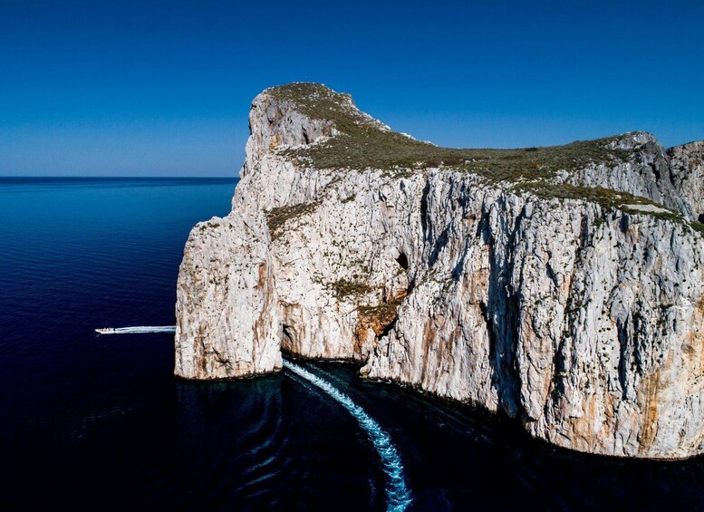 A rocky cliff with a boat navigating through a narrow passage. 1