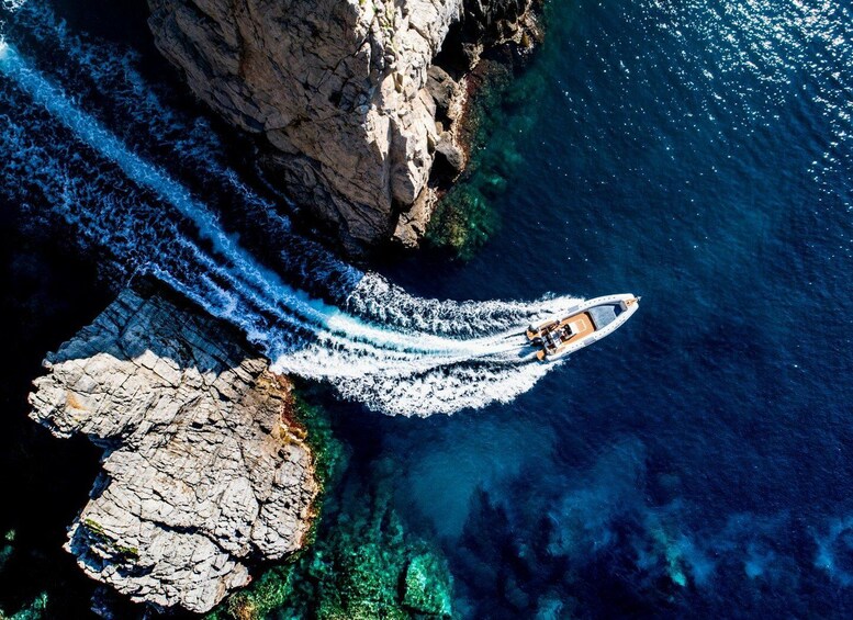 A boat speeding through clear blue waters near rocky cliffs. 5