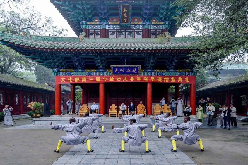 A traditional Chinese building with a red entrance and people in martial arts attire. 3