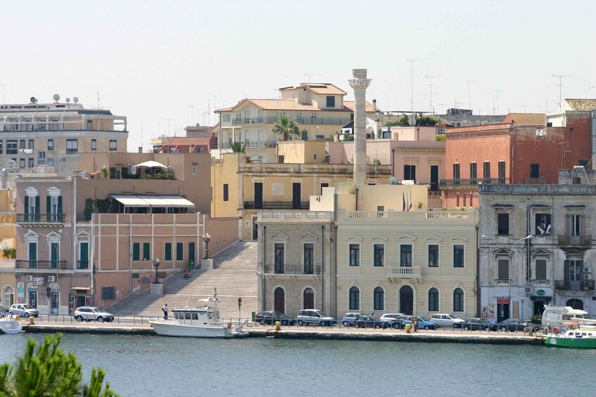 A coastal cityscape with a prominent staircase leading to a building with classical architecture, a marina with boats, and a clear sky. 2