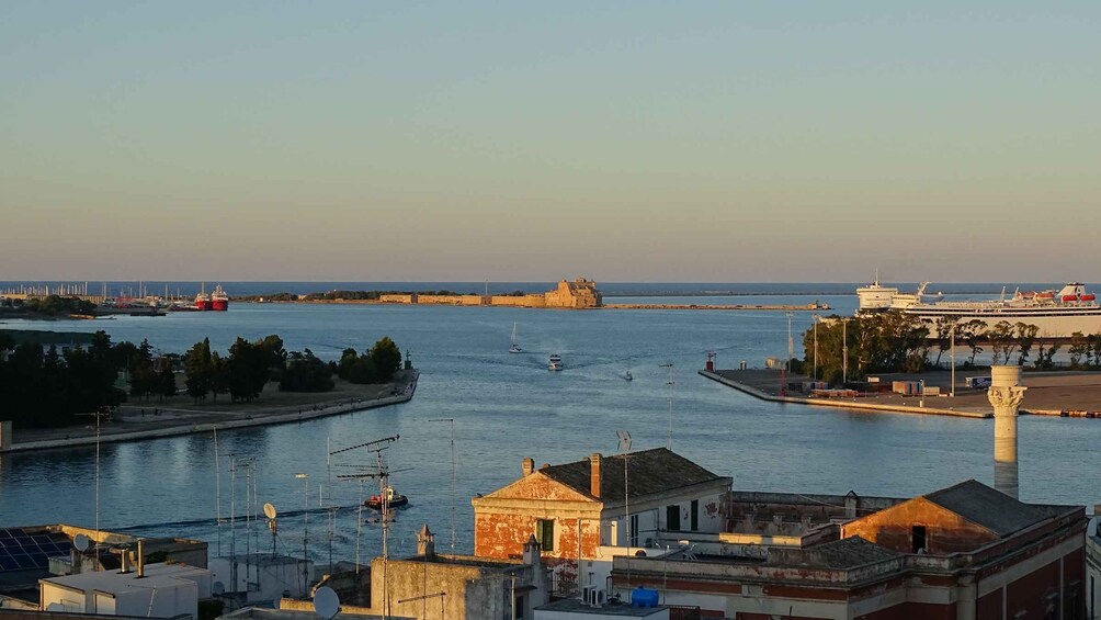 A coastal cityscape with a river, a historic fort, and a cruise ship docked at the port. 4