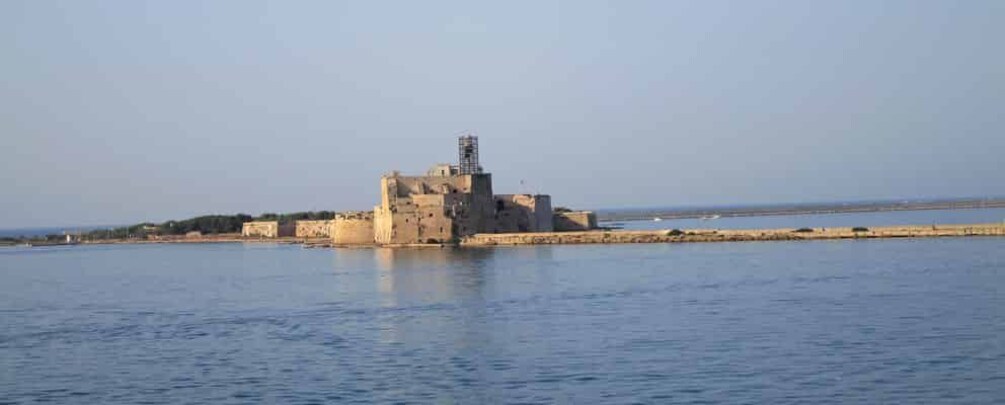 A coastal fortress with a tower, calm sea, and clear sky. 5