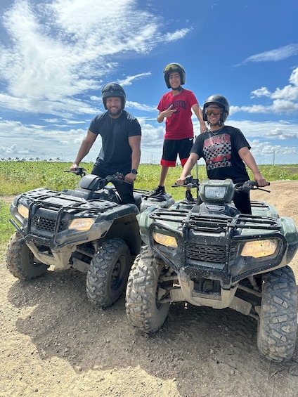 Three people on ATVs on a dirt path with a clear sky. 4