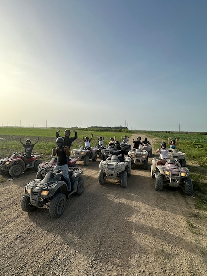 A group of people on ATVs on a dirt path with a grassy field and power lines in the background. 2