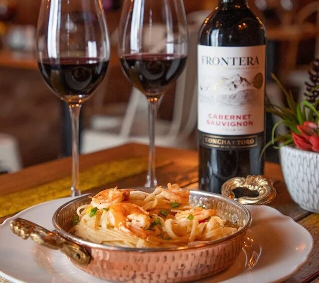 Un plat de pâtes aux crevettes, une bouteille de vin Frontera Cabernet Sauvignon et deux verres à vin. 4